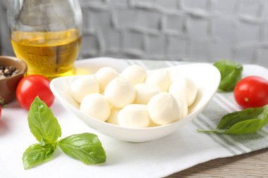 Lezzetli mozarella peynir topları, domatesler, fesleğen, yağ ve biberler ahşap masada, yakın plan.