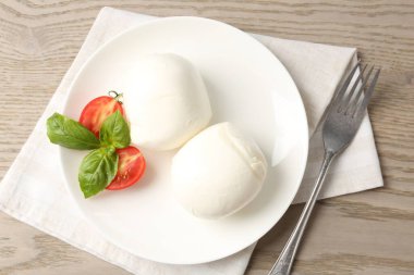 Lezzetli mozzarella peyniri topları, ahşap masada domates ve fesleğen.
