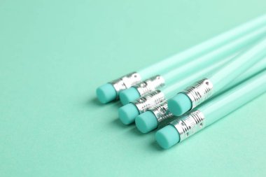 Turkuaz arka planda silgisi olan birçok grafit kalem, yakın plan. Metin için boşluk