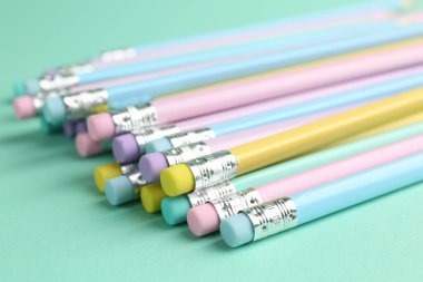 Turkuaz arka planda silgisi olan birçok grafit kalem, yakın plan