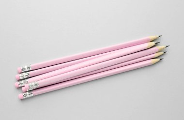 Açık gri arkaplanda silgileri olan bir sürü grafit kalem, düz konum