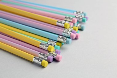 Açık gri arka planda silgisi olan birçok grafit kalem, yakın plan. Metin için boşluk