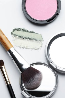 Beyaz arka planda farklı makyaj ürünleri ve fırçalar, düz konum