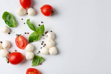 Lezzetli mozzarella topları, domatesler, biberler ve beyaz arka planda fesleğen. Metin için boşluk