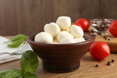 Lezzetli mozarella topları, domatesler, biberler ve fesleğenler ahşap masada, yakın plan.