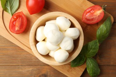 Lezzetli mozarella topları, domatesler ve fesleğenler ahşap masada, düz yatıyordu.