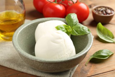 Lezzetli mozarella topları, domatesler, ahşap masada yağ ve fesleğen, yakın plan.