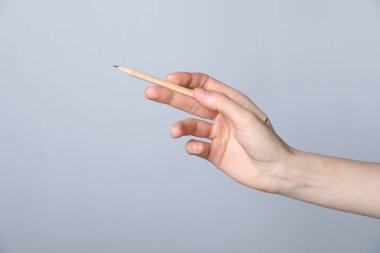 Gri arka planda grafit kalemi olan kadın, yakın plan. Metin için boşluk