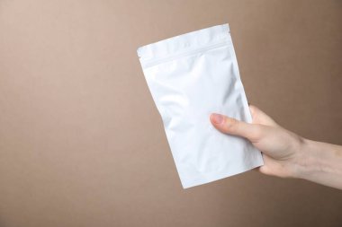 Bej arka planda fermuarlı stand-up kesesi olan kadın, yakın plan. Tasarım için model