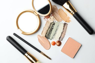 Farklı kozmetik ürünleri, makyaj fırçaları ve beyaz arka planda ayna, düz yatış