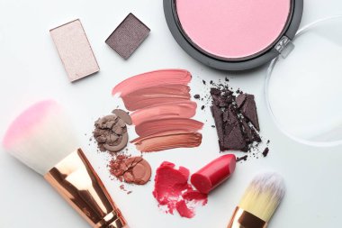 Beyaz arka planda farklı kozmetik ürünler ve makyaj fırçaları, düz yatış