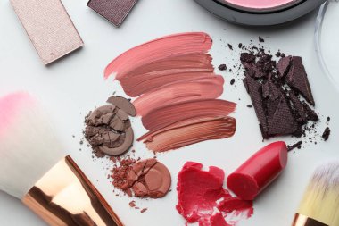 Beyaz arka planda farklı kozmetik ürünler ve makyaj fırçaları, düz yatış