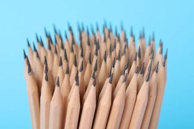 Many graphite pencils on light blue background, closeup