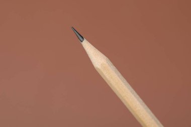 Kahverengi arkaplanda bir grafit kalem, yakın plan.