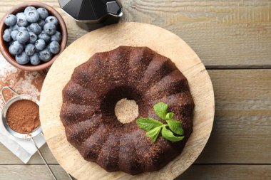 Naneli ve yaban mersinli lezzetli çikolatalı kek, ahşap masa, düz uzanmış.