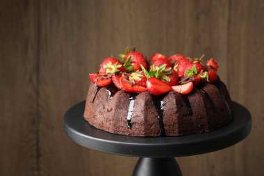 Çilekli, naneli ve çikolatalı kek bulanık arka planda duruyor, yakın planda.