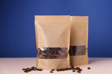 Mavi arka planda üzerinde kahve çekirdekleri olan fermuar stand-up torbaları. Tasarım için model