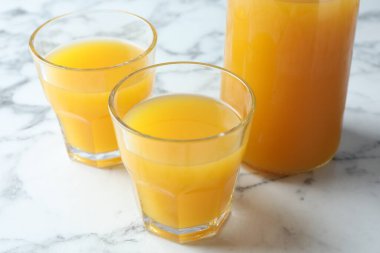 Bardakta lezzetli mango suyu ve beyaz mermer masada sürahi, yakın plan.