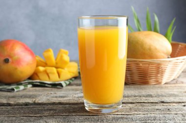 Bardakta lezzetli mango suyu ve ahşap masada taze meyve.
