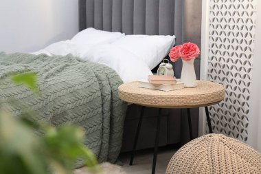 Çalar saati, kitapları ve yatağın yanında dekorasyonu olan yan masa.