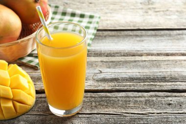 Bardakta lezzetli mango suyu ve ahşap masada taze meyveler, yakın plan. Metin için boşluk