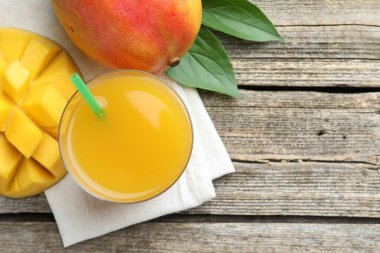 Lezzetli mango suyu bardakta, taze meyve ve yapraklar ahşap masada, düz yerde. Metin için boşluk