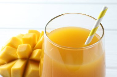 Bardakta lezzetli mango suyu ve beyaz masada taze meyve, yakın plan.