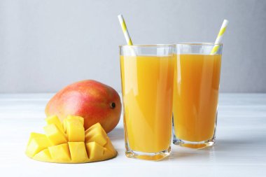 Bardakta lezzetli mango suyu ve beyaz ahşap masada taze meyve, yakın plan.