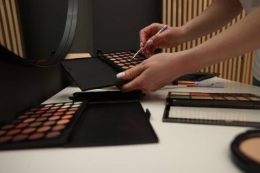 Makyaj masasında fırça ve göz falı olan kadın, yakın plan.