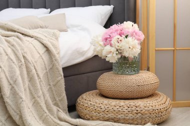 Yan masada yatağın yanında çiçekler var.