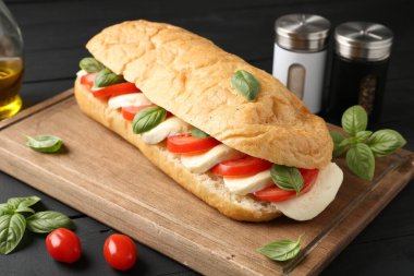 Mozarella peynirli, domatesli, fesleğenli, siyah ahşap masa, yakın plan.