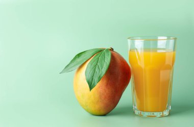 Bardakta lezzetli mango suyu ve yeşil arka planda taze meyve, metin için yer