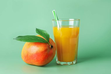 Bardakta lezzetli mango suyu ve yeşil arka planda taze meyve.