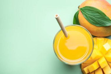 Lezzetli mango suyu bardakta ve yeşil arka planda taze meyveler düz yerde. Metin için boşluk