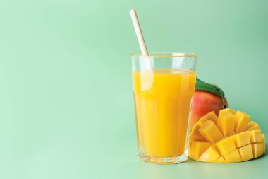 Bardakta lezzetli mango suyu ve yeşil arka planda taze meyve, metin için yer