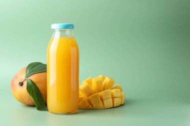 Cam şişede lezzetli mango suyu ve yeşil arka planda taze meyve, mesaj için yer var.