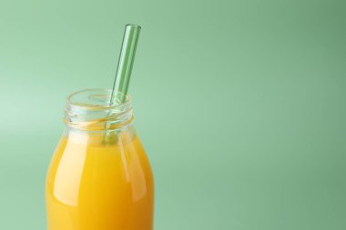 Yeşil arka planda cam şişede lezzetli mango suyu, yakın plan. Metin için boşluk