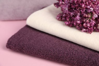 Yumuşak havlular ve pembe arka planda leylak çiçekleri, yakın plan.