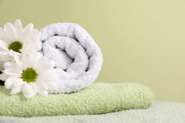 Yumuşak havlular ve soluk yeşil arka planda kasımpatı çiçekleri, yakın plan.