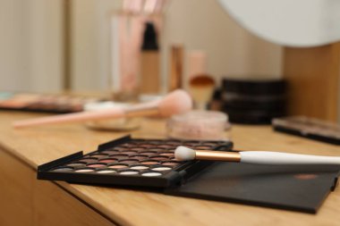 Göz farı paleti ve ahşap masada fırça, yakın plan.