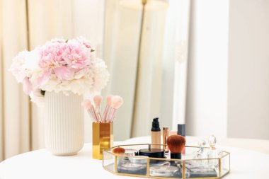 Beyaz masadaki farklı makyaj ürünlerinin olduğu tepsi. Metin için boşluk