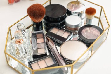 Farklı makyaj ürünleri olan tepsi beyaz masada, yakın plan