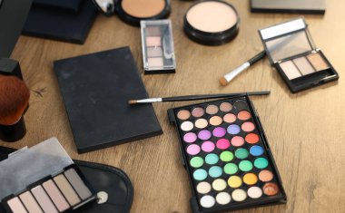 Ahşap masada farklı makyaj ürünleri, yakın plan.