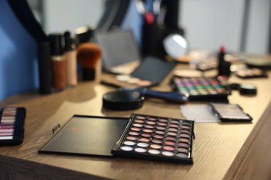 Kapalı alanda, ahşap masada farklı makyaj ürünleri.