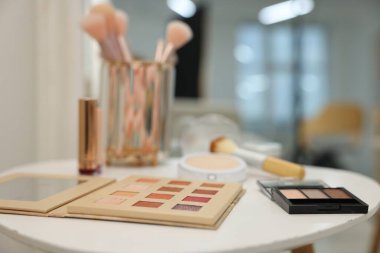 Beyaz masadaki farklı makyaj ürünleri ve fırçalar.