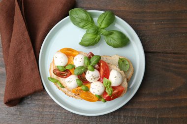 Peynirli, domatesli, ahşap masadaki fesleğenli lezzetli sandviç.