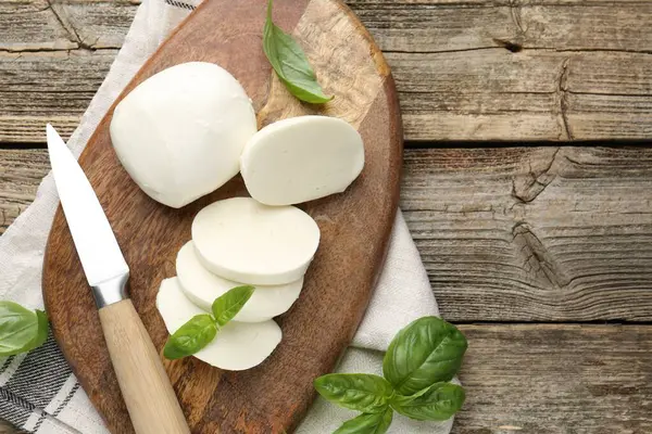 Ahşap masada fesleğen ve bıçakla mozzarella peyniri kes. Metin için boşluk