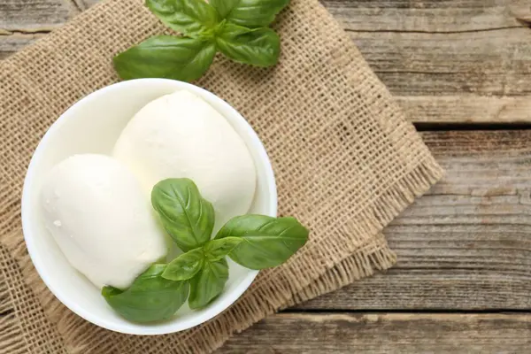 Ahşap masada mozzarella peyniri ve fesleğen var. Metin için boşluk