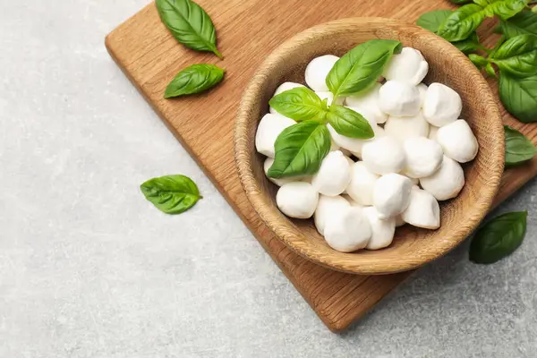 Mozzarella peyniri topları ve fesleğen açık gri masada, düz yerde. Metin için boşluk