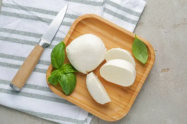 Lezzetli mozarella peyniri parçaları, fesleğen yaprakları ve bıçak gri desenli masa, düz yatıyordu.